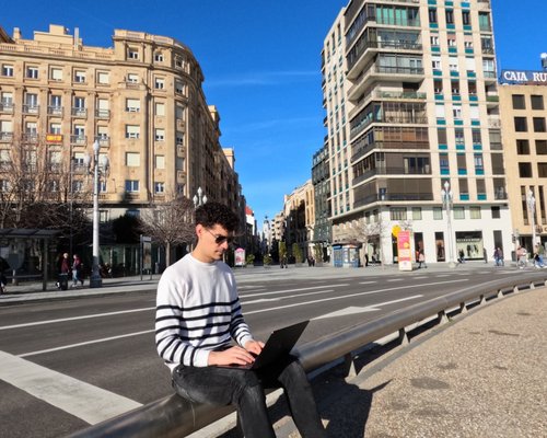 person working on a laptop beside a bright window in Spain